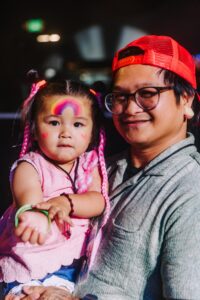 A father and his daughter with face paint at a rave.