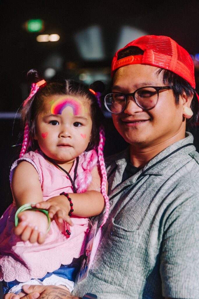 A father and his daughter with face paint at a rave.