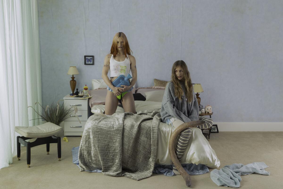 Rhian Teasdale and Hester Chambers pose on a bed.