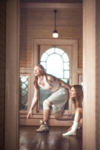 Rhian Teasdale and Hester Chambers of Wet Leg crouch walk across a hallway.