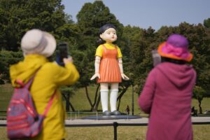 Visitors take photos near a model of the doll named 'Younghee'  featured in Netflix's series "Squid Game"