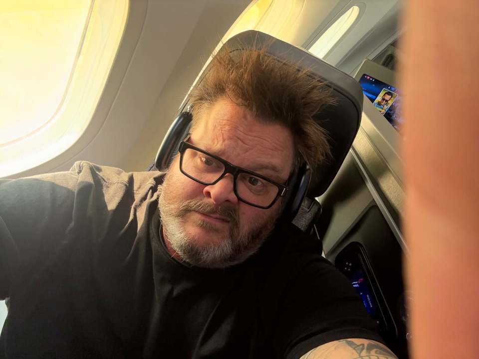 Man wearing glasses and headphones on airplane.