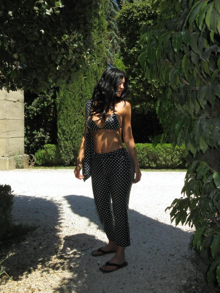 Woman in polka dot bikini and pants outdoors.