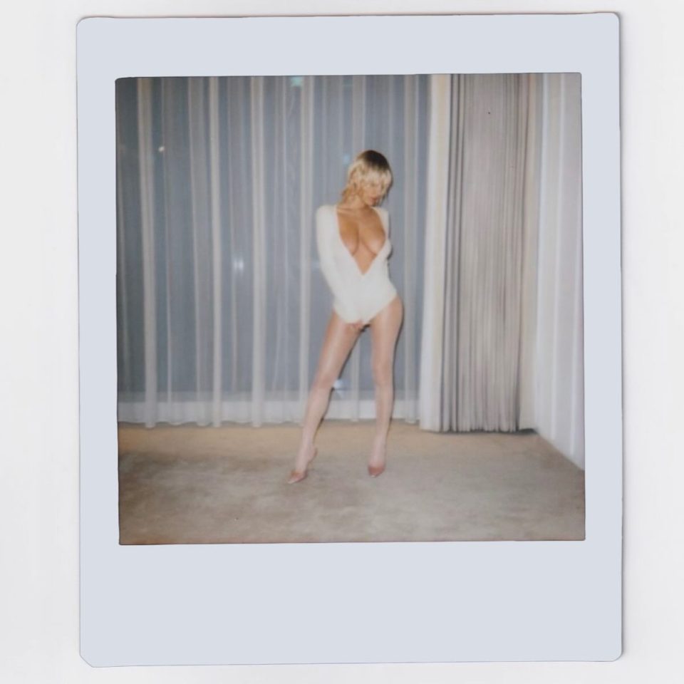 Polaroid photo of Bianca Censori in a white jumpsuit.