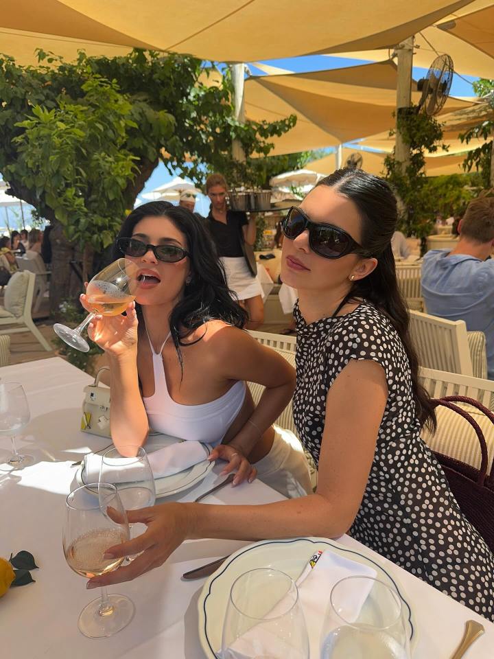 Kendall and Kylie Jenner enjoying wine at an outdoor restaurant.