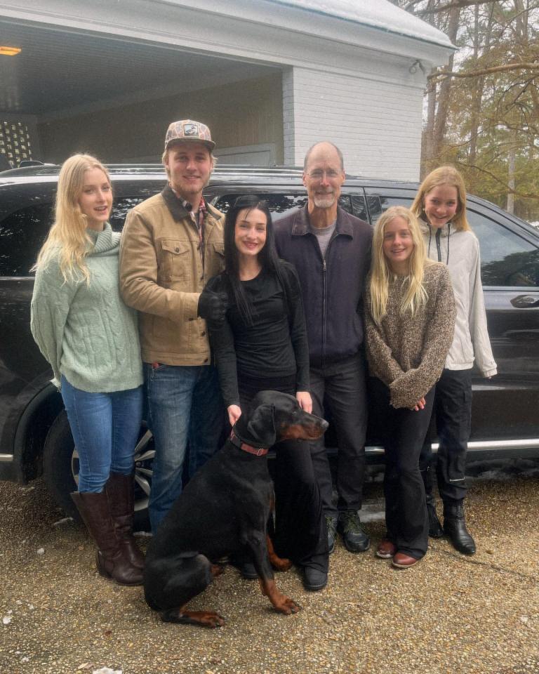 Family portrait with a dog in front of a car.