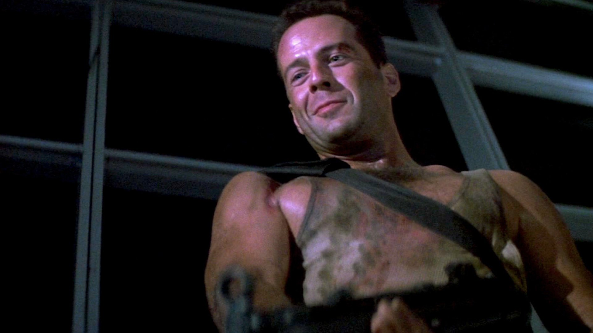 John McClane (Bruce Willis) in Die Hard, filthy and battered and smirking