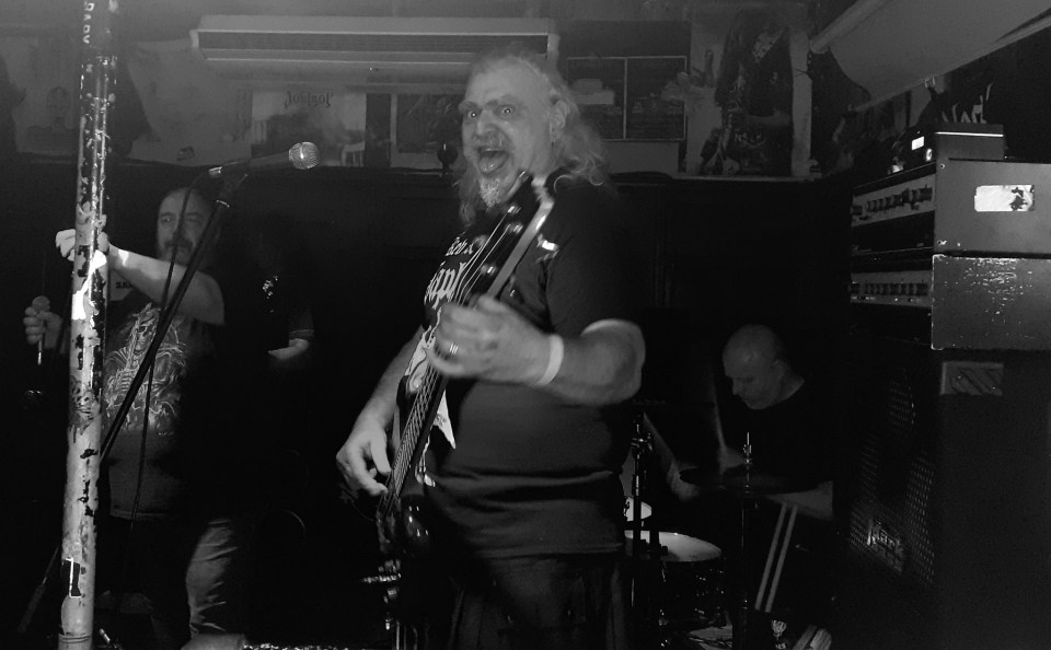 Black and white photo of a band performing; the bassist is center frame.
