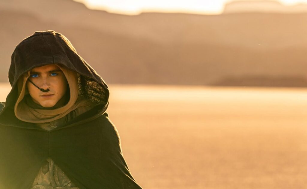 Paul Atreides, eyes spice blue, stands alone in the desert