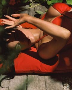 Woman in red bikini lying on a red cushion.