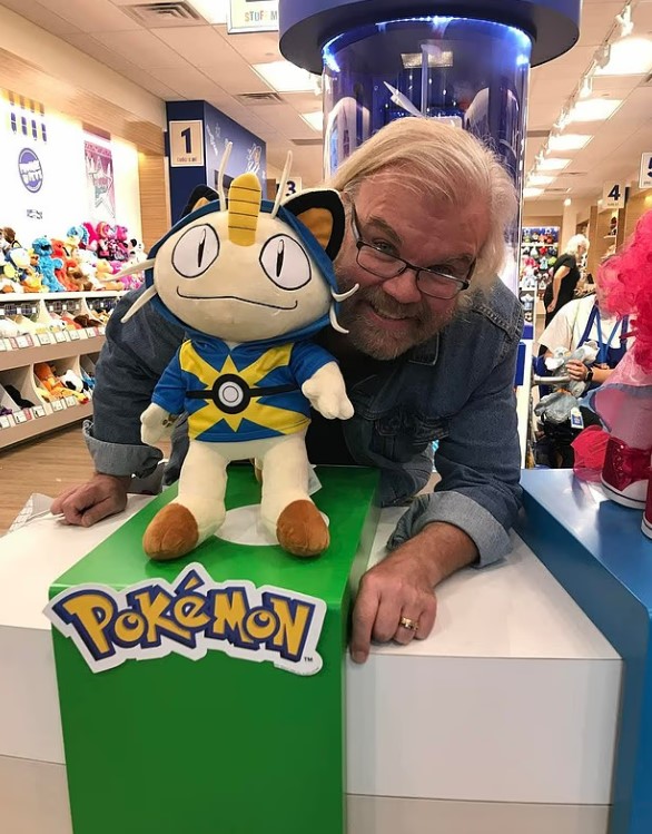 Man posing with a Mewtwo Pokémon plush.