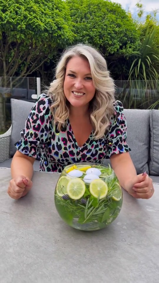 Woman sitting at a table with a glass bowl of lemons, herbs, and floating candles.
