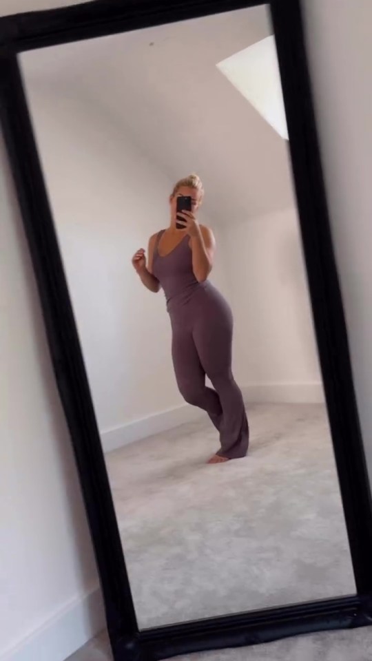 Woman in purple jumpsuit reflected in a mirror.