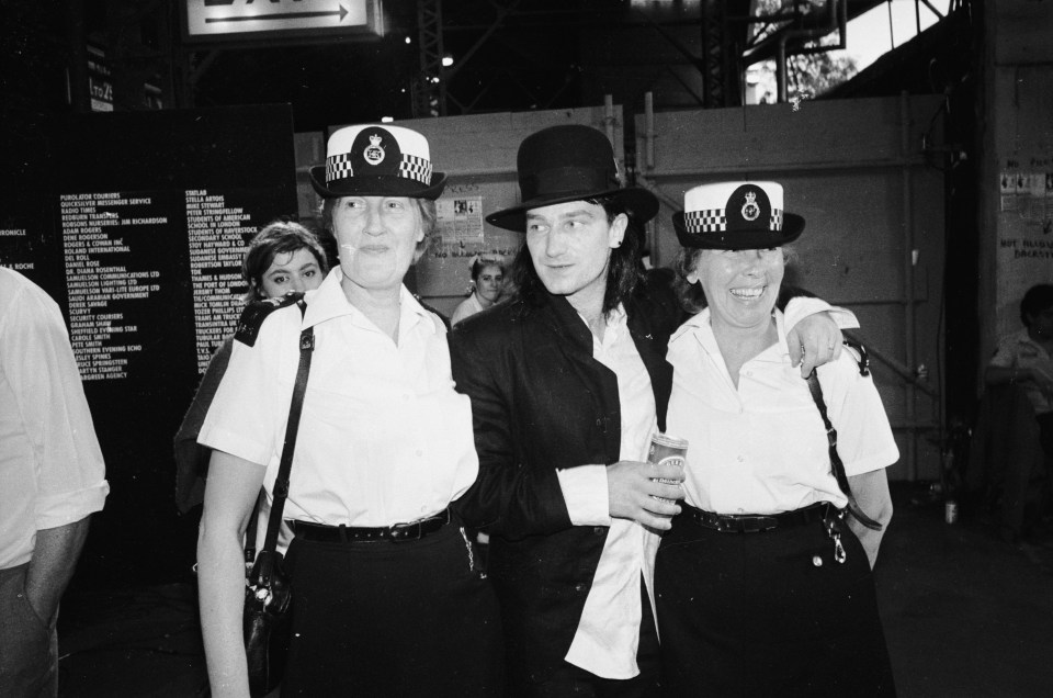 Bono of U2 backstage at Live Aid with two policewomen.
