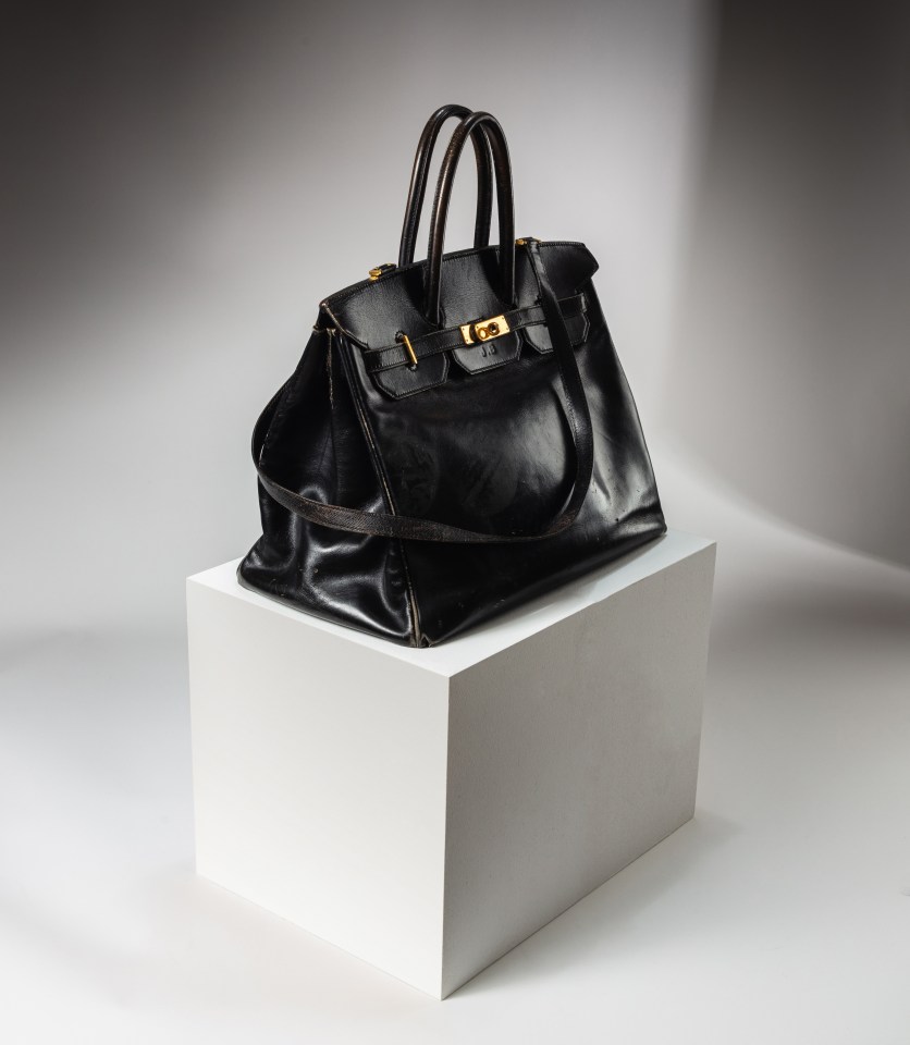 Black Hermès Birkin bag on white pedestal.