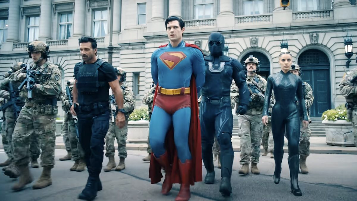 Ultraman, tje Engineer, and Rick Flag Sr accompany a handcuffed Superman along with soldiers