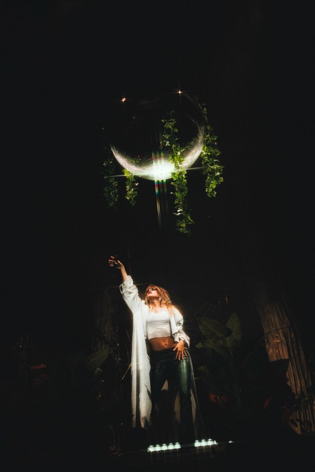 Suki Waterhouse on stage with a disco ball.