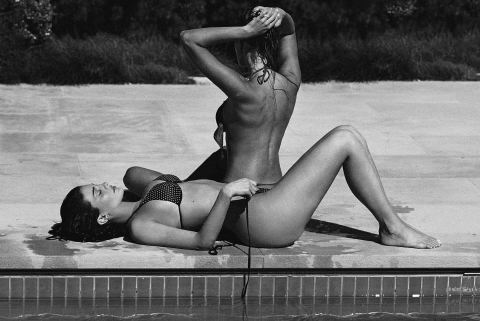Black and white photo of two women in bikinis by a pool.