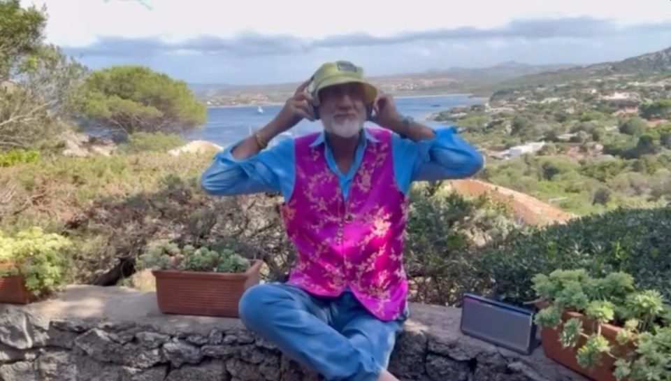 Lindsey Buckingham putting on headphones outdoors.