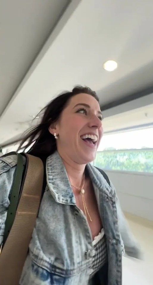 Woman smiling and walking in an airport after receiving flight compensation.