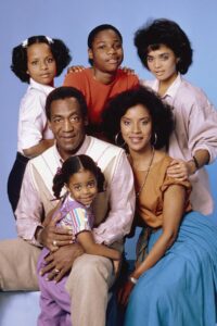 A couple sits as four children surround them.