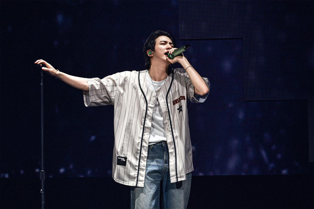 Jin sporting his baseball jersey merch onstage at Honda Center