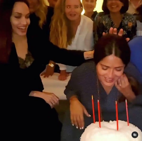 Angelina Jolie playfully pushes Salma Hayek's face into a birthday cake.