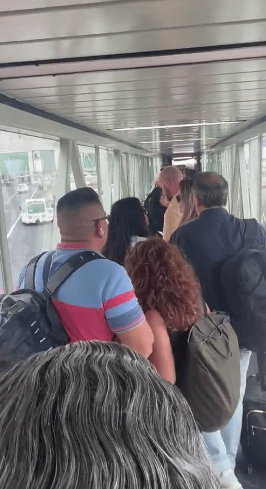 Passengers walking down an airport jet bridge.