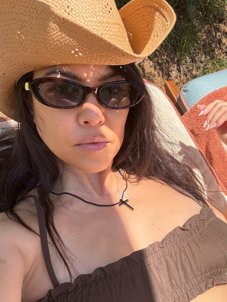 Kourtney Kardashian in a brown bikini top, sunglasses, and cowboy hat.