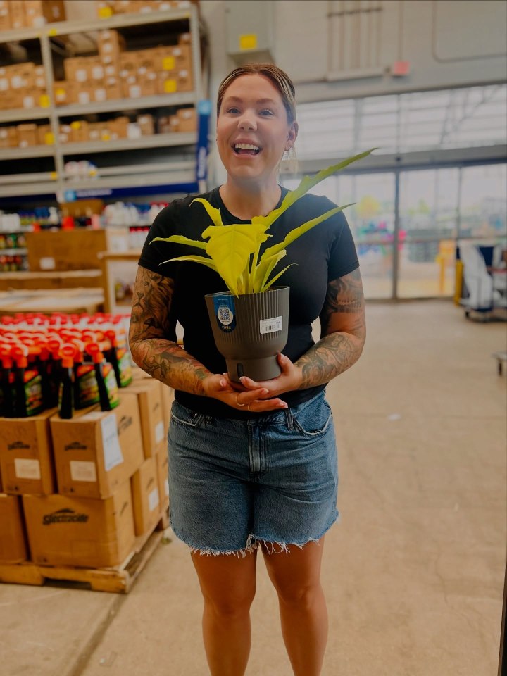 Woman holding a yellow plant in a gray pot.