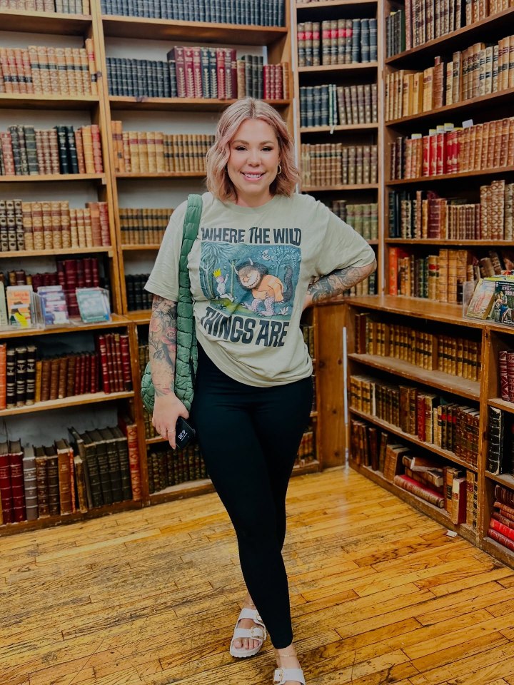 Woman in "Where the Wild Things Are" shirt standing in a bookstore.