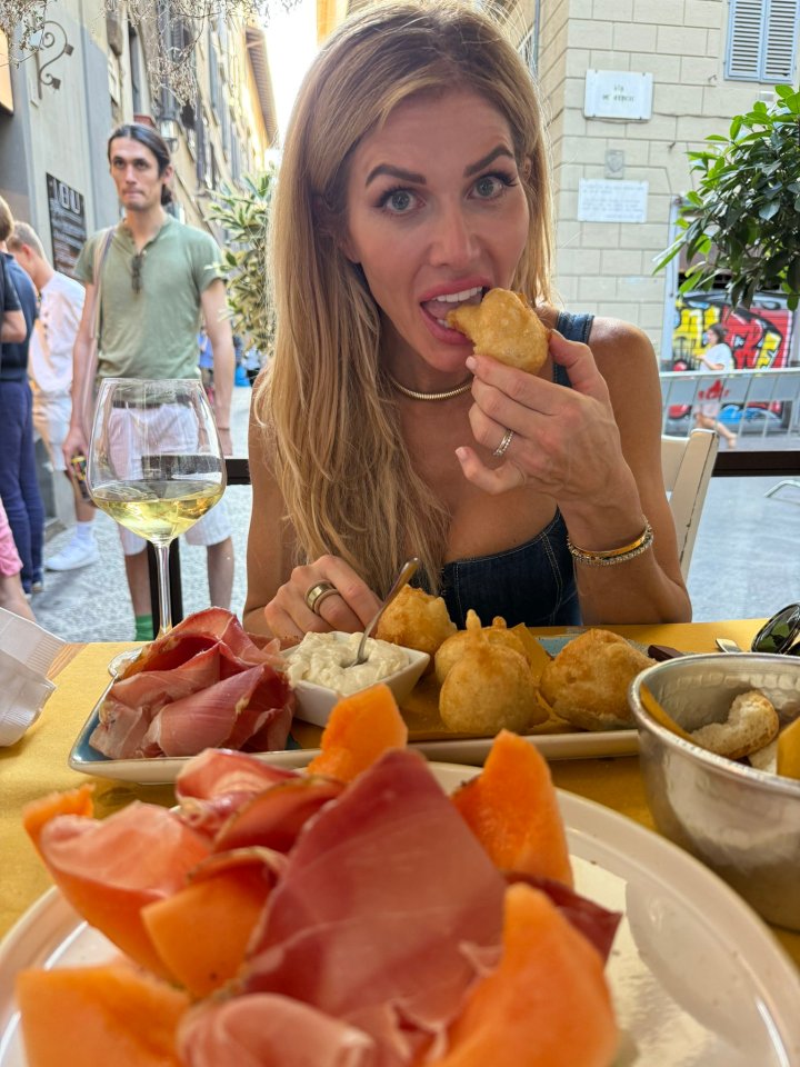 Woman eating fried dough and prosciutto with melon in Italy.