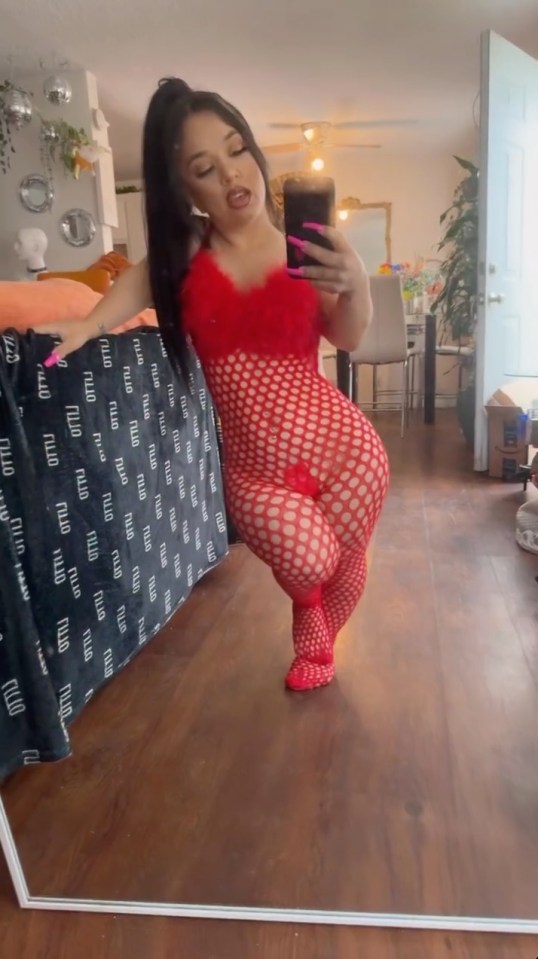 Woman in red fishnet bodysuit taking a selfie.