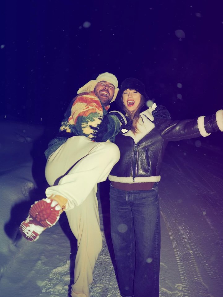 A man playfully carries a woman in the snow at night.