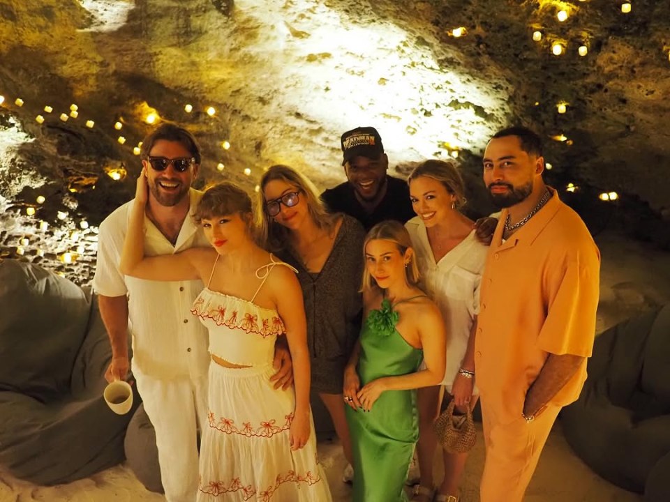 Group photo of Taylor Swift and friends in a cave lit by candles.