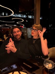 Taylor Swift and a man sitting at a restaurant table.