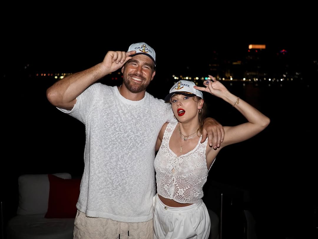 Travis Kelce e Taylor Swift usando os chapéus de capitão combinando.