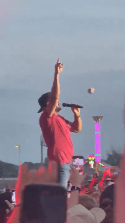 Luke Bryan performing on stage, hit in the face by a flying object.