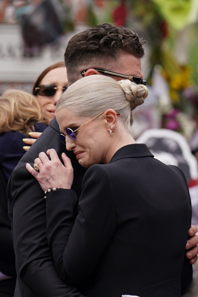 Kelly and Jack Osbourne embrace at a memorial.
