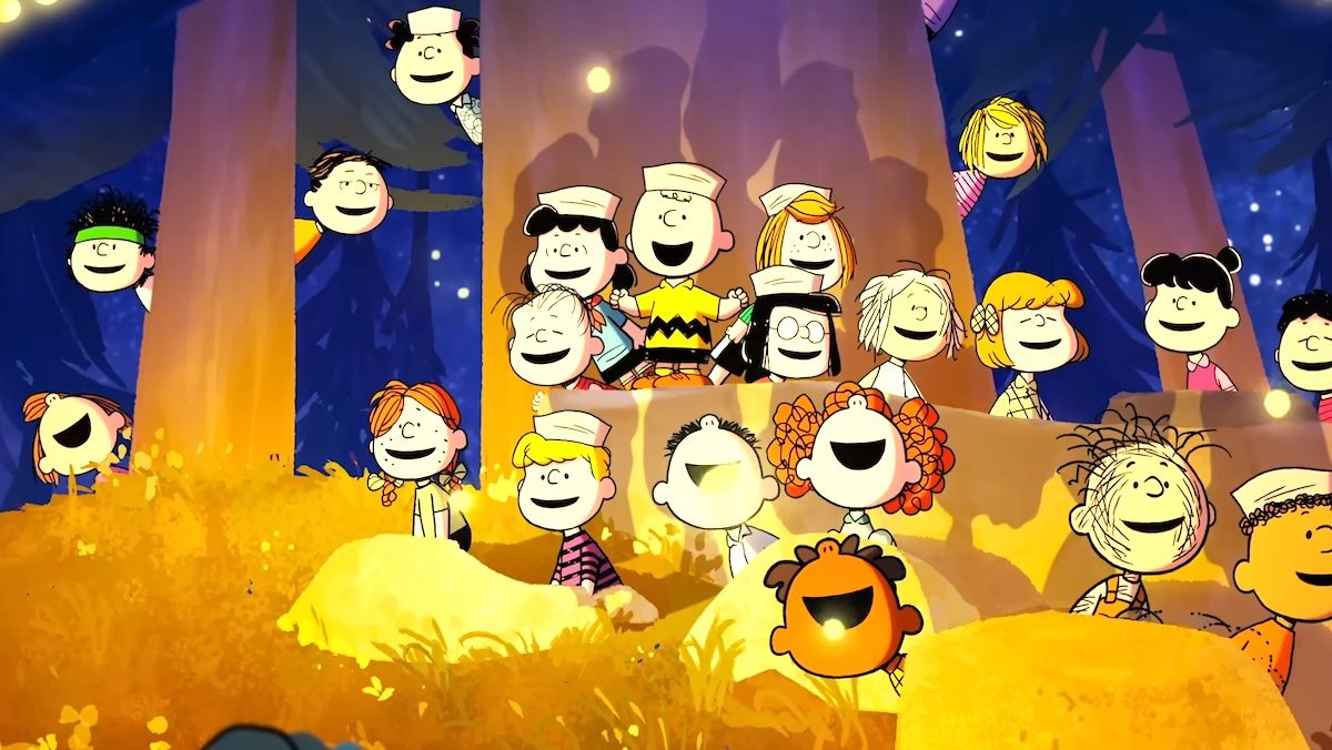 Charlie Brown y Peanuts Niños cantando cerca de un árbol y fuego en Snoopy Presents: A Summer Musical