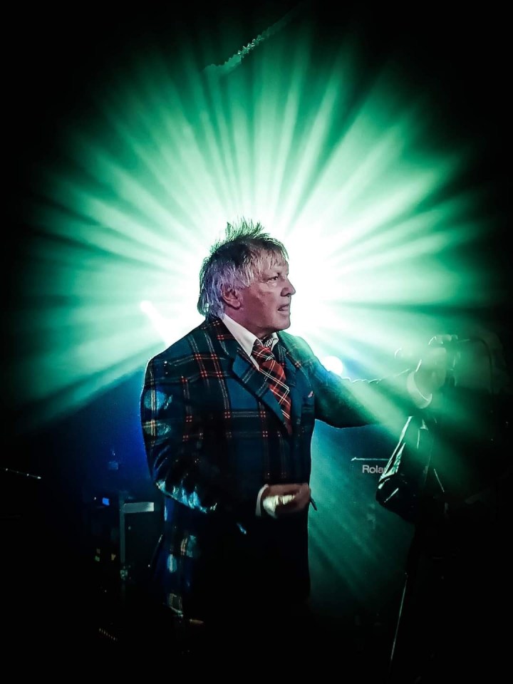 Man in plaid suit performing on stage.