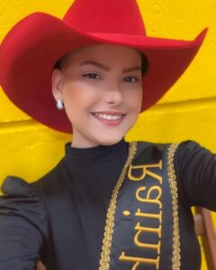 Portrait of Camila Trevisol, a rodeo queen, wearing a red cowboy hat and sash.