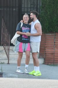 Jojo Siwa and Chris Hughes holding hands and smiling.