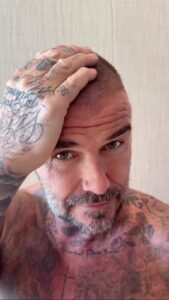 David Beckham touching his buzzed head.