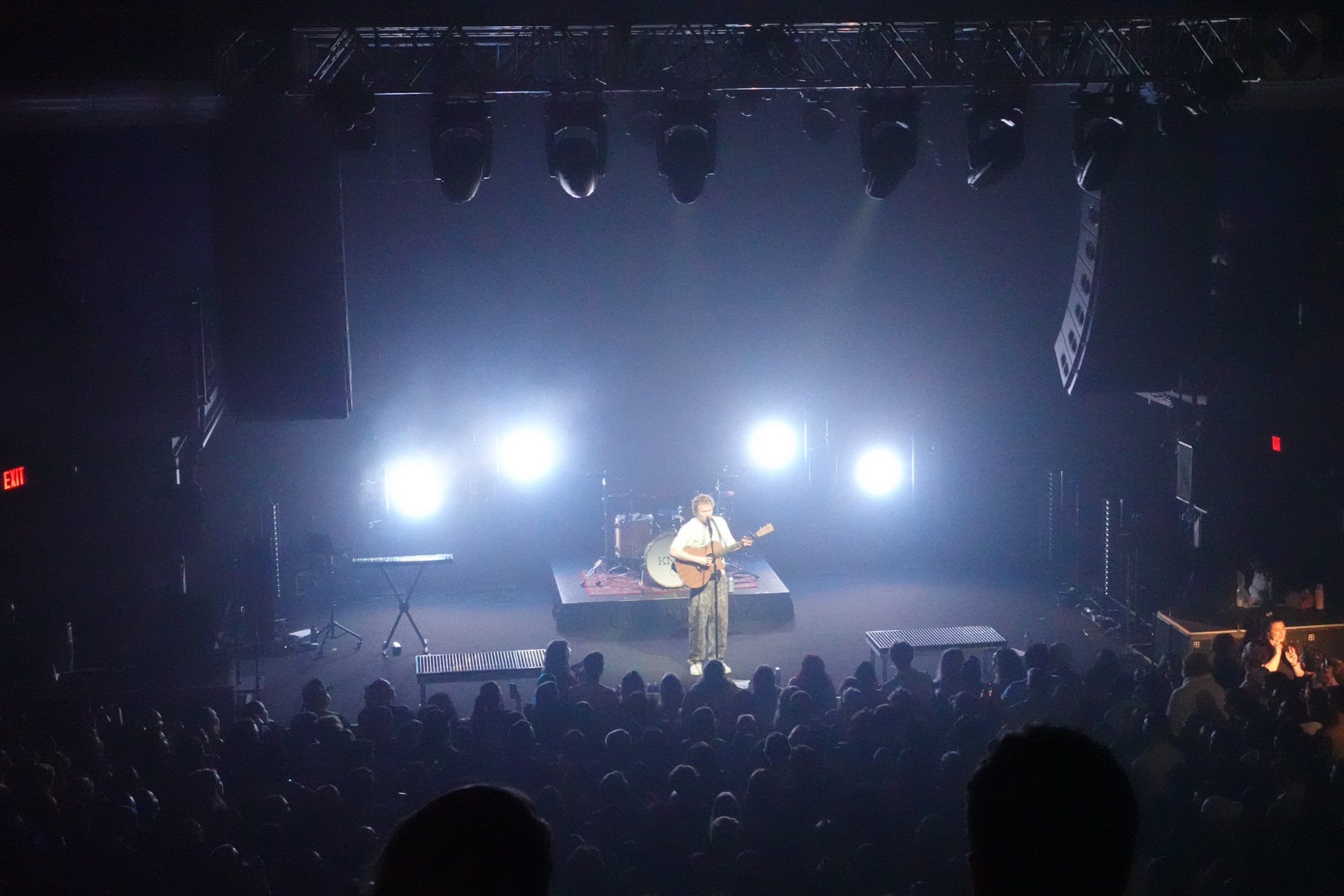 Knox performing on stage alone with a guitar to a full audience.  