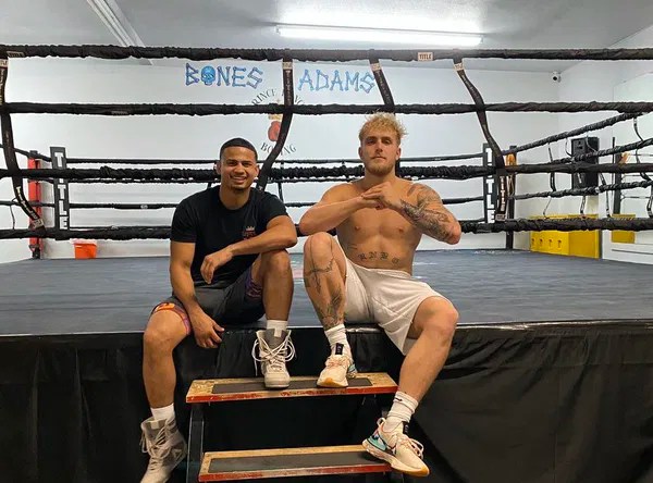 Two men sitting on steps in a boxing ring.