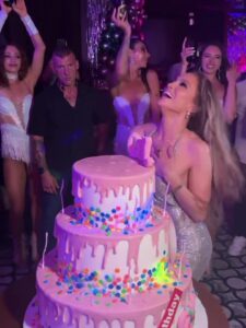 Jennifer Lopez at her 56th birthday celebration with a large multi-tiered cake.