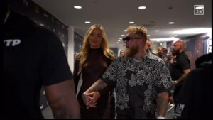 Couple holding hands walking down a hallway.