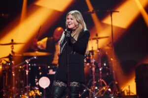 Kelly Clarkson performing onstage at a concert.