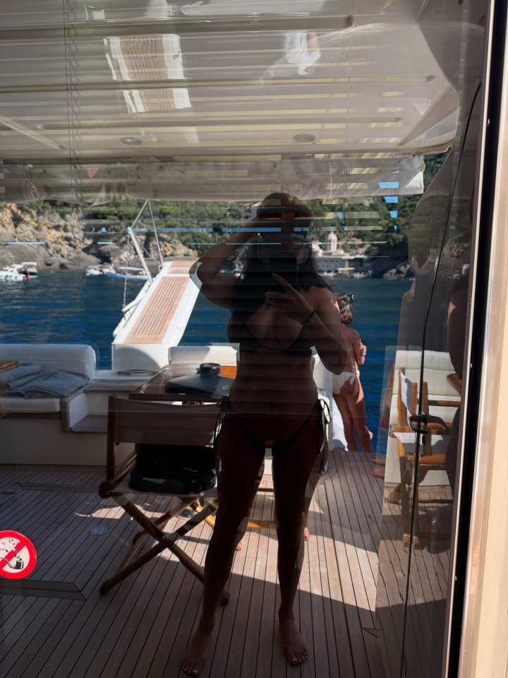 Reflection of a woman in a bikini taking a selfie on a yacht.